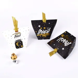 Détail de boîtes cadeaux blanches et noires avec des étoiles dorées et écrit Merci