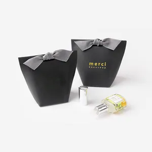 Minimalist black matte pillow gift boxes with grey silk bows and gold merci beaucoup text