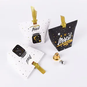 Détail de boîtes oreillers noires et blanches avec lettrage Merci doré et cloches