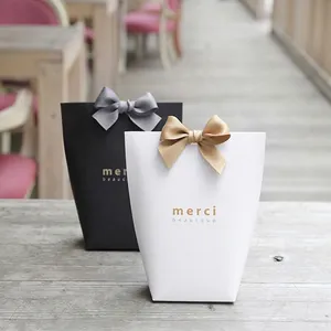 White and black specialty paper gift bags with merci gold foil and silk ribbon bows