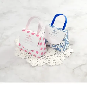 Détail de mini boîtes cadeaux en forme de sac à main avec poignées en soie et motifs