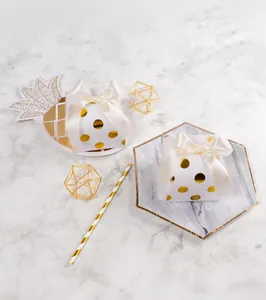 Macro shot of white gift box with gold dots and a cream satin bow on marble texture