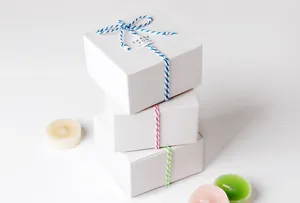 Nahaufnahme von dreisträngigem Baumwollgarn auf weißem Geschenkkarton mit Dankesanhänger