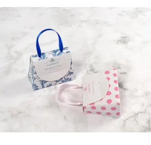 Gros plan de mini boîtes cadeaux en forme de sac à main avec poignées en soie et motifs