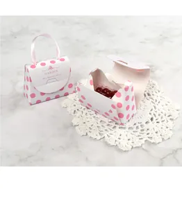 Détail de mini boîte cadeau à pois roses avec poignée en ruban sur fond de marbre