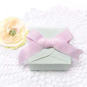 Detalle de caja de regalo verde menta con cinta a rayas rosa sobre fondo de encaje blanco