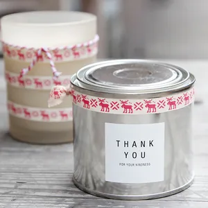 Close-up of red Christmas reindeer ribbon and Thank You sticker on a metal gift tin