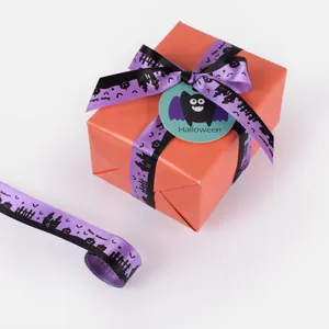 Detail of purple Halloween ribbon with pumpkin and castle prints on orange gift box