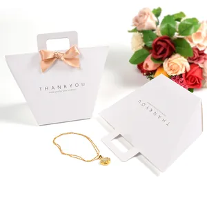 Weiße trapezförmige Geschenktüte mit goldener THANK YOU Prägung und Satinschleife