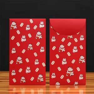 Enveloppes rouges du Nouvel An chinois avec motifs Maneki-neko sur une table en bois