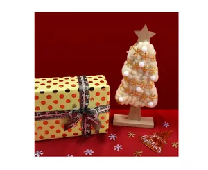 Close-up of white plush Christmas tree with golden snowflake ribbon and wooden base