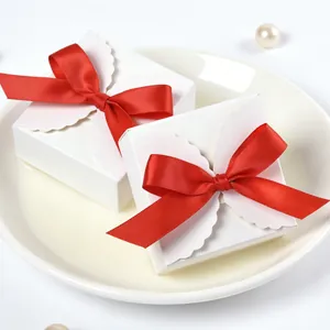 Macro shot of square white gift box with red satin bow and wavy edge lid design