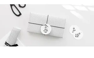 Close-up of round white gift tag with smile icon and black elastic string for packaging