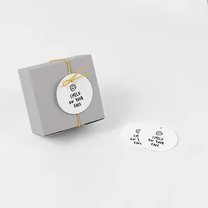 Grey gift box with smile face tags and yellow elastic cords for elegant packaging
