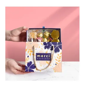 Detail view of floral gift box with gold handles and 'merci beaucoup' text for favors
