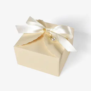 Detail of cream wedding gift box with scalloped edges, white satin bow and pearl charm
