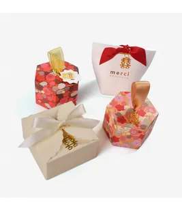 Detail of luxury wedding candy boxes with metallic Xi pendants and satin ribbons