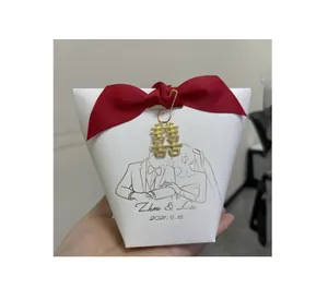 Close-up of white wedding favor box with red bow and golden Double Happiness metal charm
