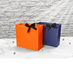 Détail de sacs cadeaux de mariage de luxe orange et bleu marine avec poignées dorées