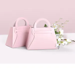 Detalle de cajas de regalo trapezoidales rosa claro con asa para bodas