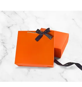 Détail d'un ensemble de boîtes cadeaux de mariage orange avec un élégant ruban noir