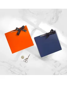 Vue de dessus de boîtes cadeaux de mariage orange et bleu marine avec ruban et bougies