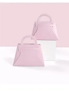 Detalle de bolsas de regalo de papel rosa trapezoidales con asas para bodas