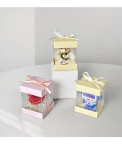 Tre scatole regalo quadrate con finestre trasparenti con rosa, orsetto e figurina di robot