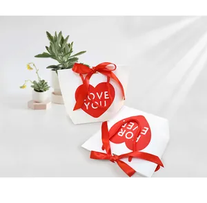 Detail of white paper gift bags with red heart prints and decorative satin ribbon bows