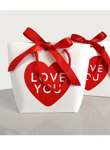 Close-up of white gift bag with red heart, LOVE YOU text and satin ribbon bow detail