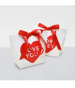 Detail of white gift paper bag with red heart, satin bow and rope handles for Valentine's Day