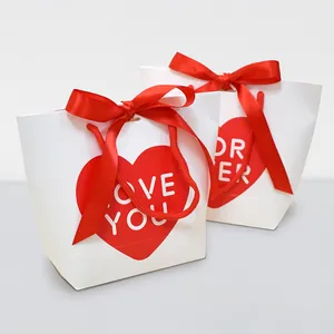 Minimalist white gift bag with red heart and satin bow for Valentine's Day packaging