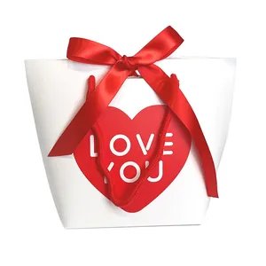 Minimalist red heart paper gift bag with silk bow and Love You print on white background