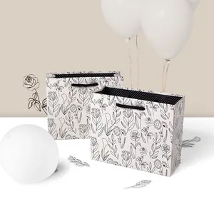 Sac cadeau carré minimaliste en papier avec motifs floraux et poignées tissées noires