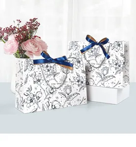Close-up of floral line art gift bags with navy blue satin bow and All the best text