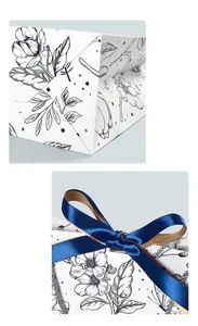 Detail of premium paper gift bag with floral ink art and a blue-gold silk ribbon bow