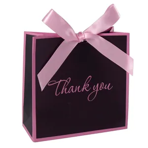 Minimalistische schwarze Geschenkpapiertüte mit großer rosa Satinschleife und Aufschrift