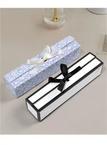 Detail van rechthoekige geschenkdozen met strikken voor pennen en horloges in bloemen en zwart