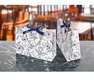 Detail of floral line art gift bag with blue ribbon bow and silver woven handles