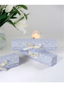 Detail van lichtblauwe damast geschenkdozen met crèmekleurige lintstrikken en bloemen