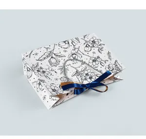 Detailed view of floral gift bag featuring blue silk bow and woven rope handles