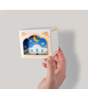 Close-up of a small white gift box featuring Islamic architecture and moon cutout