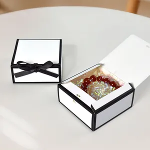 Minimalist square white gift box with black ribbon bow and interior filler for jewelry