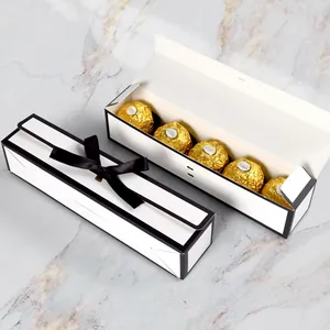 Elegante weiße rechteckige Schokoladenboxen mit schwarzen Schleifen auf Marmor