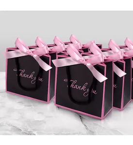 Close-up of black matte gift bag with pink bow ribbon and Thank You print detail
