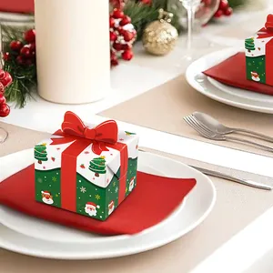 Mini Christmas gift boxes with red bows and festive patterns on a dinner plate setting