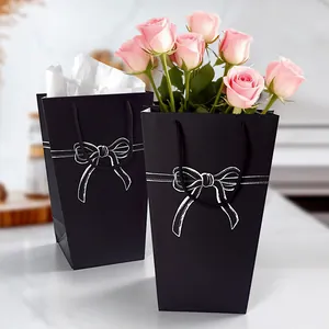 Minimalist black trapezoid paper gift bag with white bow pattern and flower packaging