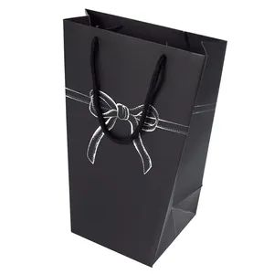 Minimalist black trapezoid gift bag with white bow design and woven rope handle