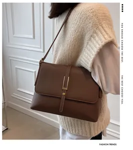 Detail of vintage brown leather shoulder bag with gold metal buckle on a model