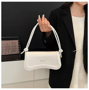 Detail of white leather shoulder bag with wave base, knot strap, and metal accents
